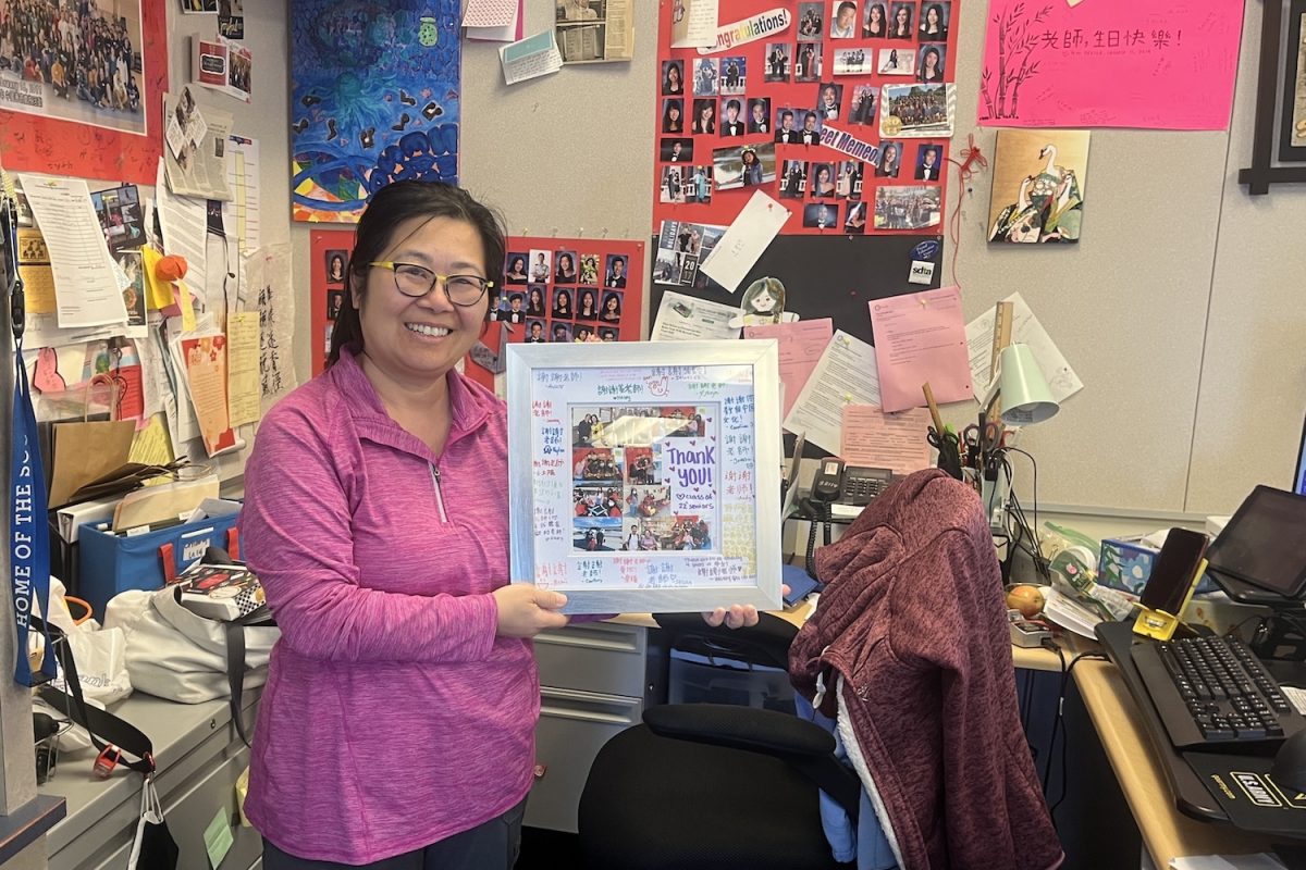 Mindy Chiang holding up a collage she received from one of her previous classes of students. 
My most memorable gift was when the class of 2022 got together and made a book of appreciation letters that looked like our textbook. They also made me a collage with signatures throughout the frame,” Chiang said. 
