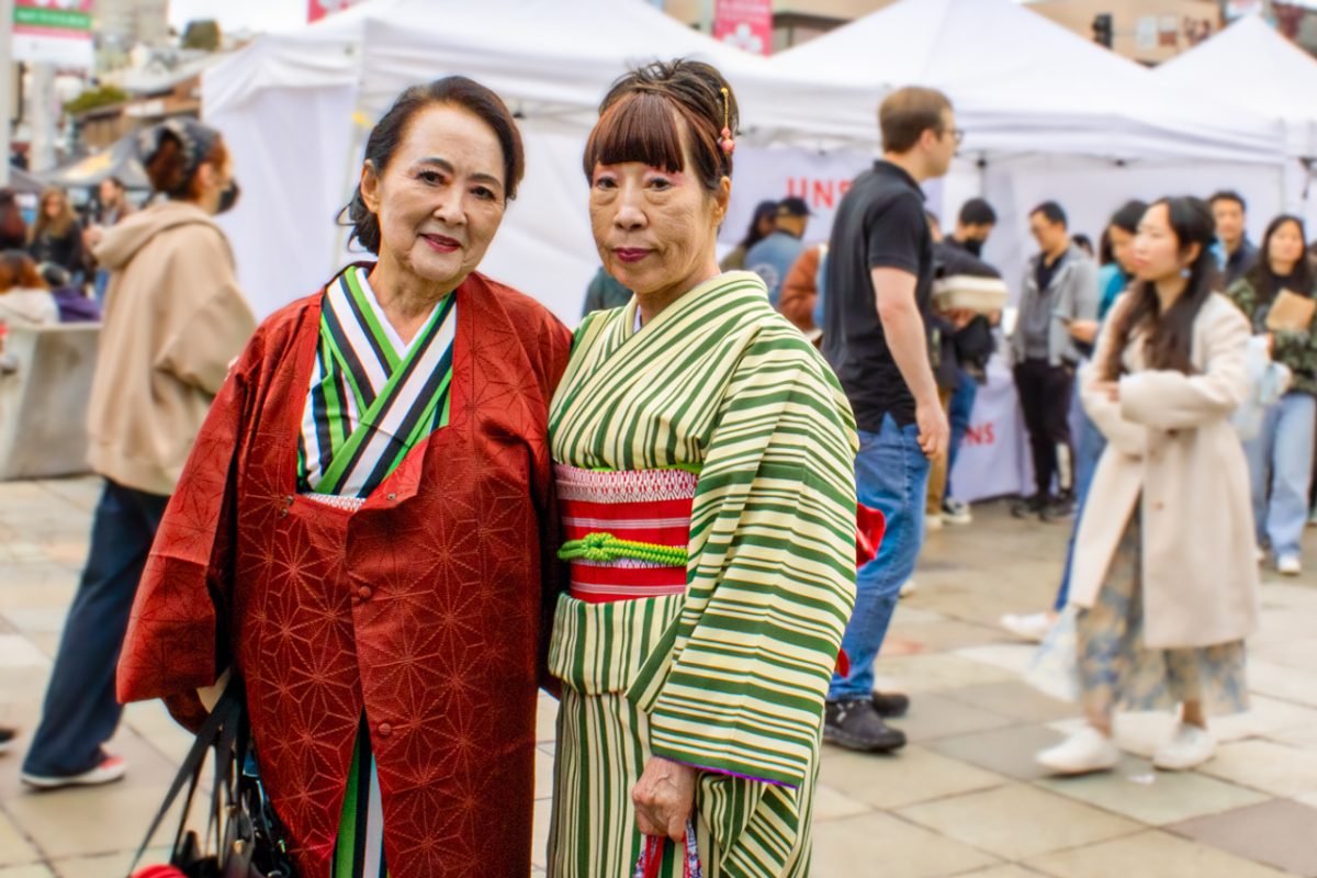 Two women wear kimonos to the Cherry Blossom Festival. Kimonos are some of the most well known of Japanese traditional garb and are characterized by a long robe, folded left over right across the torso, which is fastened by an obi, or broad belt.