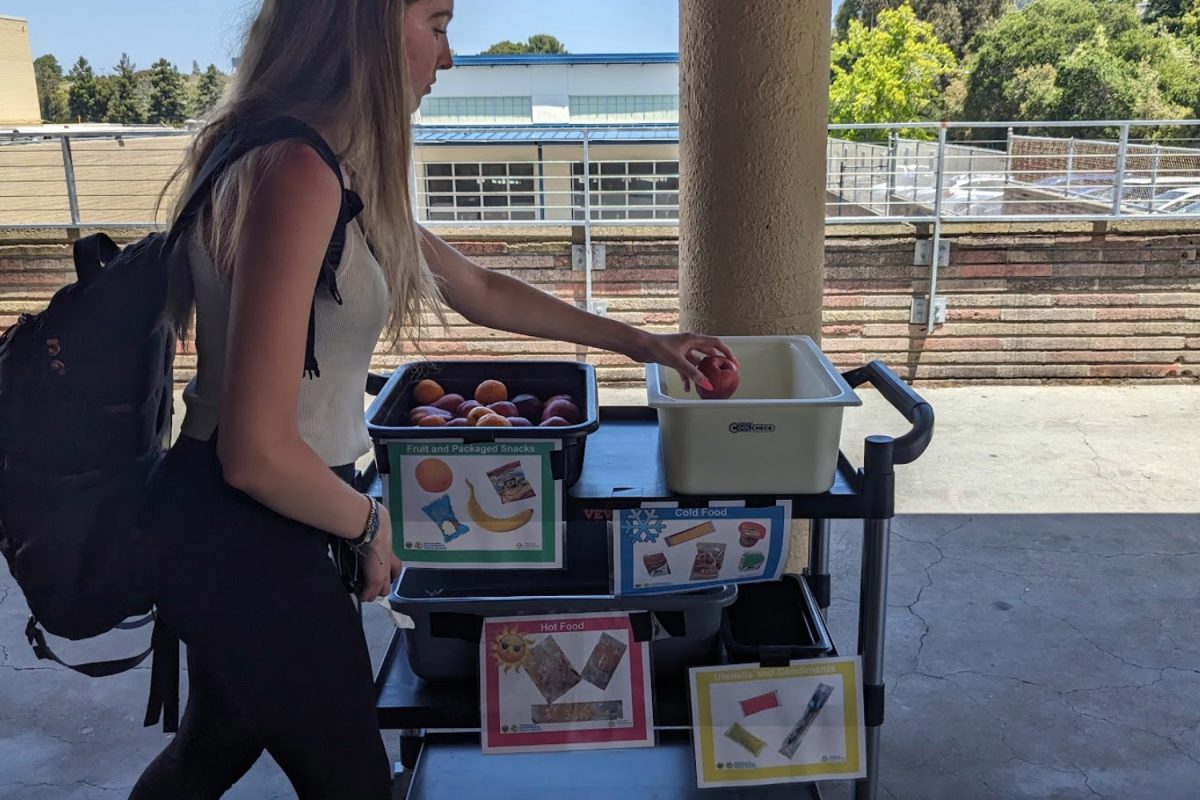 A Carlmont student puts unwanted food in the share bins at lunchtime. The bins are sectioned into fruit/packaged snacks, cold food, hot food, and utensils and condiments. Sometimes I put stuff in the share bin so others can have them, said Vanessa McMahon. 