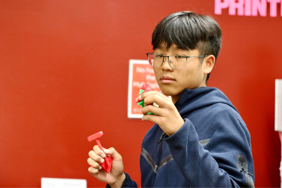 Freshman Matthew Lum inspects his newly 3D-printed pieces. He was in the librarys Makerspace room right after school to get a head start on the lengthy process. Im making a board game for my biology final, and Im glad I can use the 3D printer to make all the pieces, Lum said.