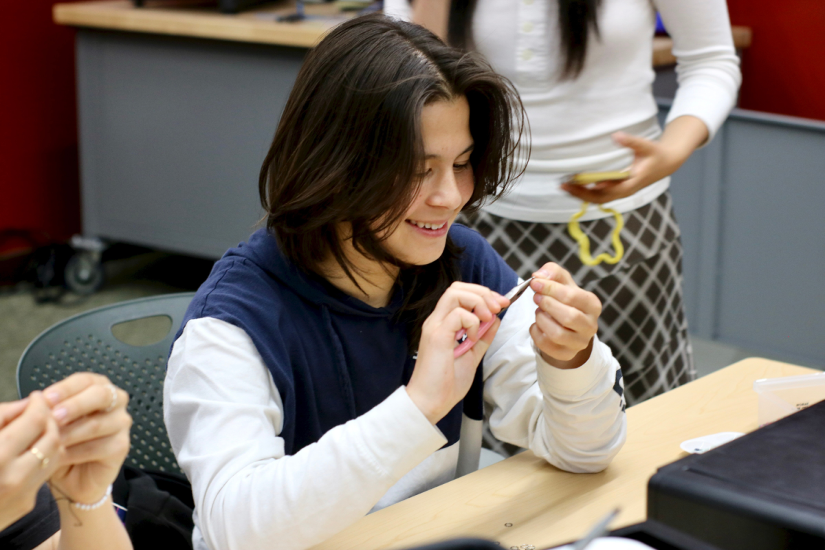 Sophomore Ria Smilovitz starts beading a bracelet. She was already in the library after school with two friends. They entered the Makerspace room after the librarian set up all the craft materials.