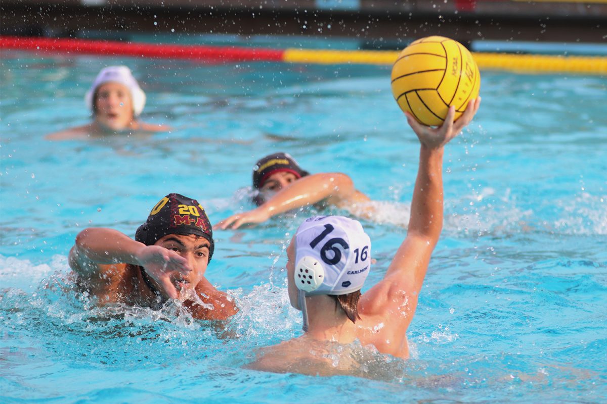 Junior Sinjin Roelle prepares to toss the ball over a defensive player. Both Carlmont and Menlo-Atherton faced heavy defensive pressure throughout the game. Interceptions were frequent on both sides. 