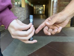 A student dealer discretely passes a vape pen to a customer. 