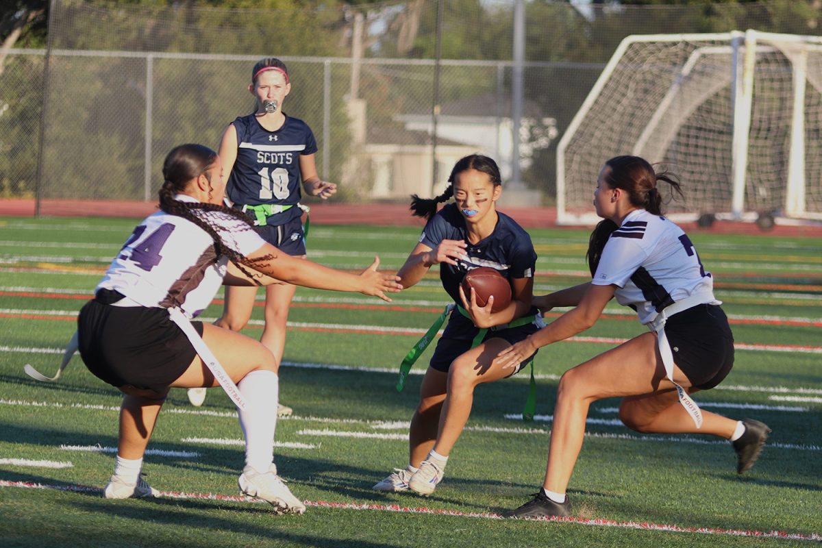 Quarterback Lauren Greene hands off the ball to running back Samantha Tow. Tow evaded the defenders as she got the first down for the Scots. She made three touchdowns this game. 