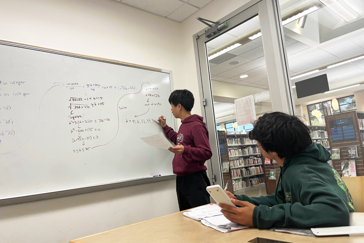 Dennis Yang explains a practice problem while another student listens at the library. "Having multiple people work on the same problem allows for deeper insight," Yang said. "It helps me understand how there might be more efficient ways to solve a problem."