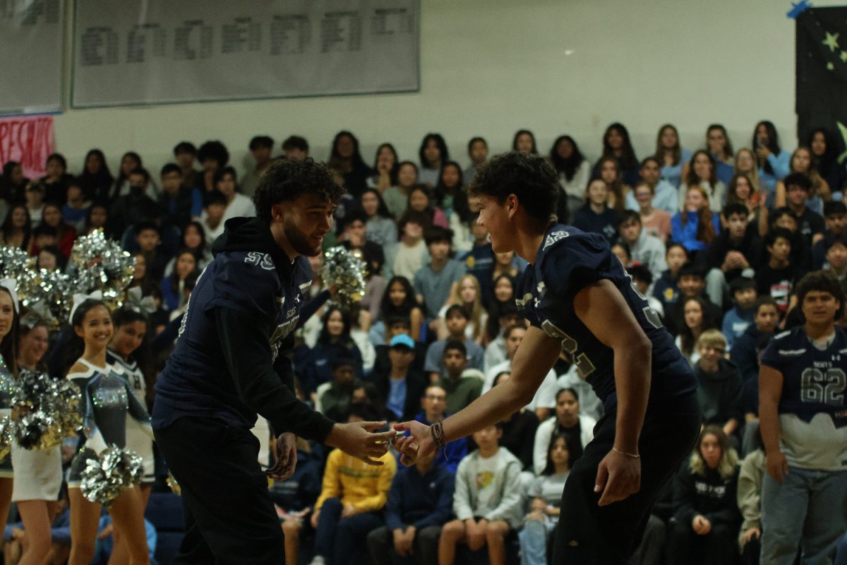 Two football players participate in a handshake during the varsity football team's rally segment of the assembly.