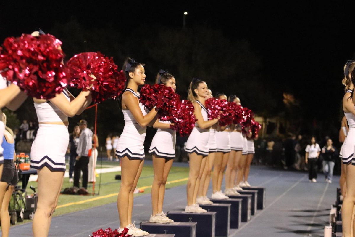 The varsity cheer team smile big as they uplift the crowd. 