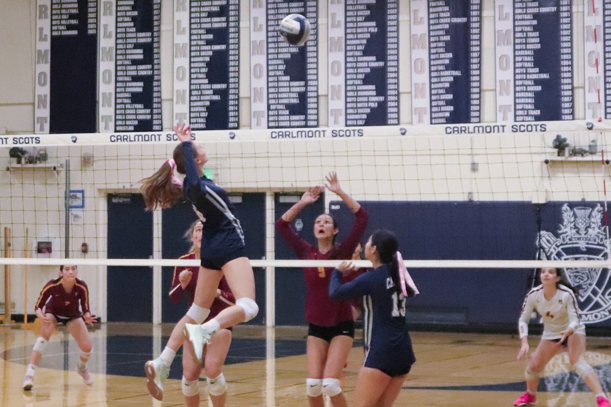 Junior Noelle Pecavar rises above the net to spike the ball after a set from teammate Ashlyn Wong. An opposing player tried to jump and block it but was unable to get there in time. Pecavar scored the point for the Scots.