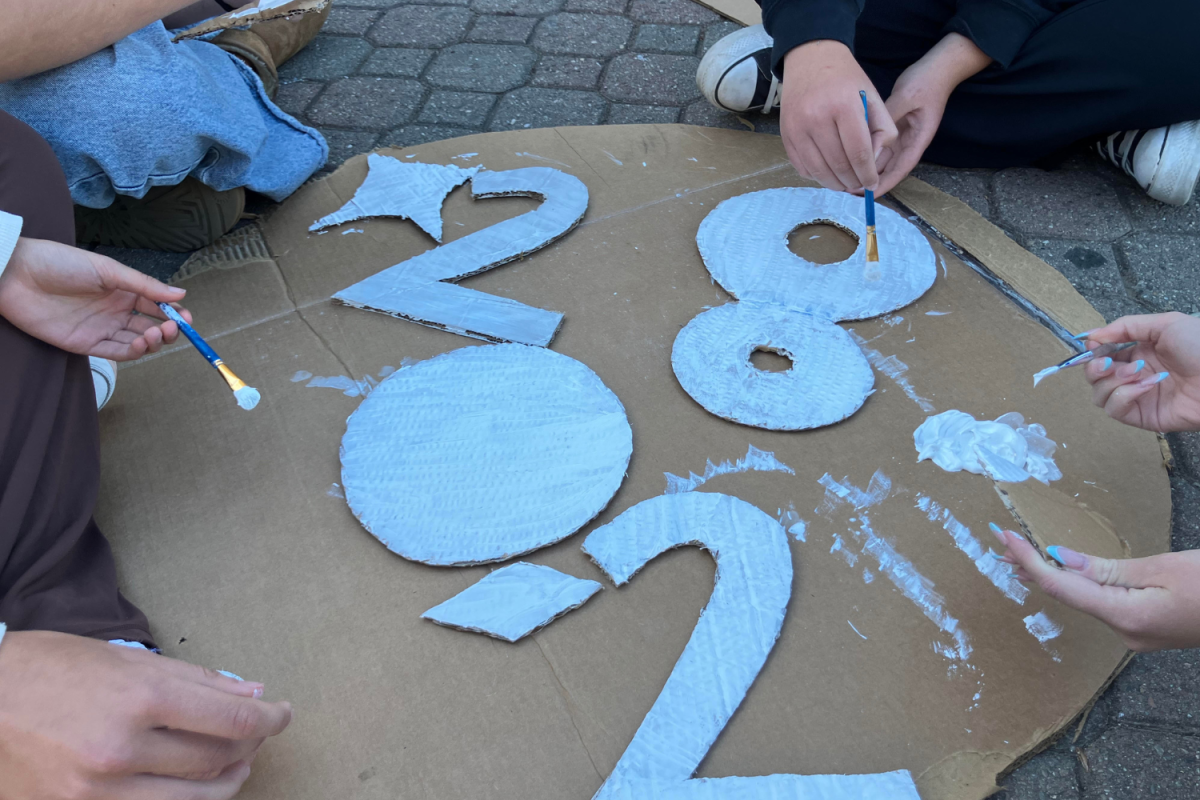 Katie Michaels, Louisa Rich-Gayko, Ellen Goetz, and Kylie Gallagher collaborate on a component of the freshman float. The numbers they are painting indicate their graduating year, 2028.