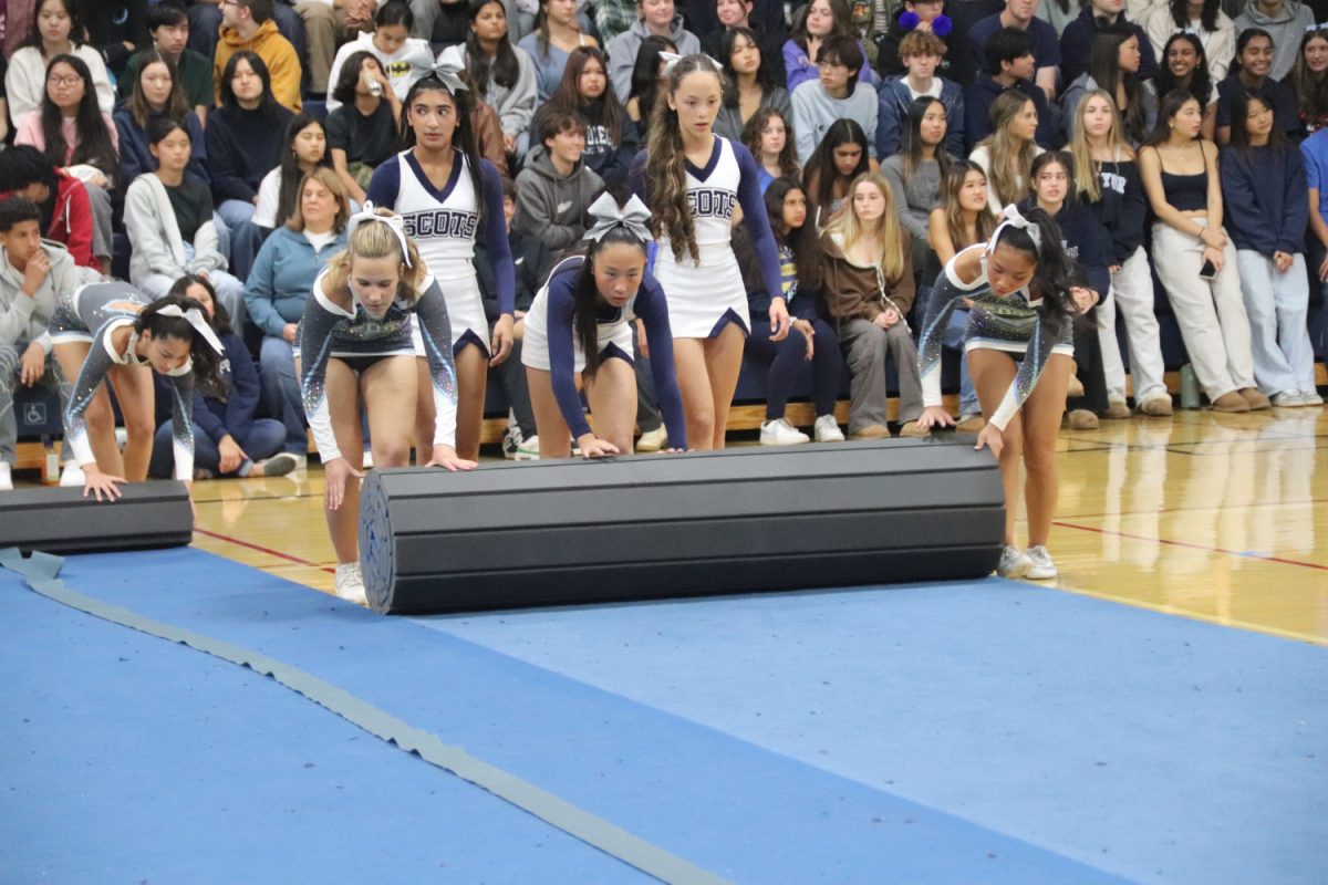 Varsity and JV cheerleaders work together to clear the tumbling mats after their segment in the assembly. For their performance, they had to set up their mats so that they could perform their stunts safely.