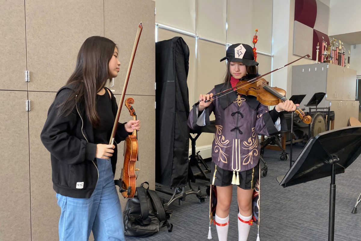 Xiaoyu Lin observes a mentee as they tune their violin. Lin is a freshman starting her first year as a mentor teaching violin.