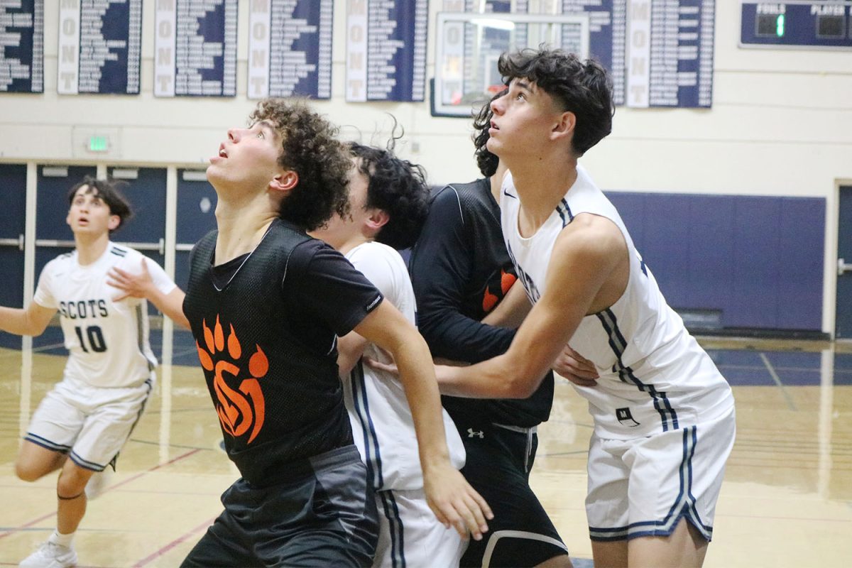 The Scots and Bearcats watch as the ball falls through the hoop, both teams positioning themselves for the rebound. The Scots secured the rebound and quickly pushed the ball down the court. This play helped them maintain their lead during the quarter. 