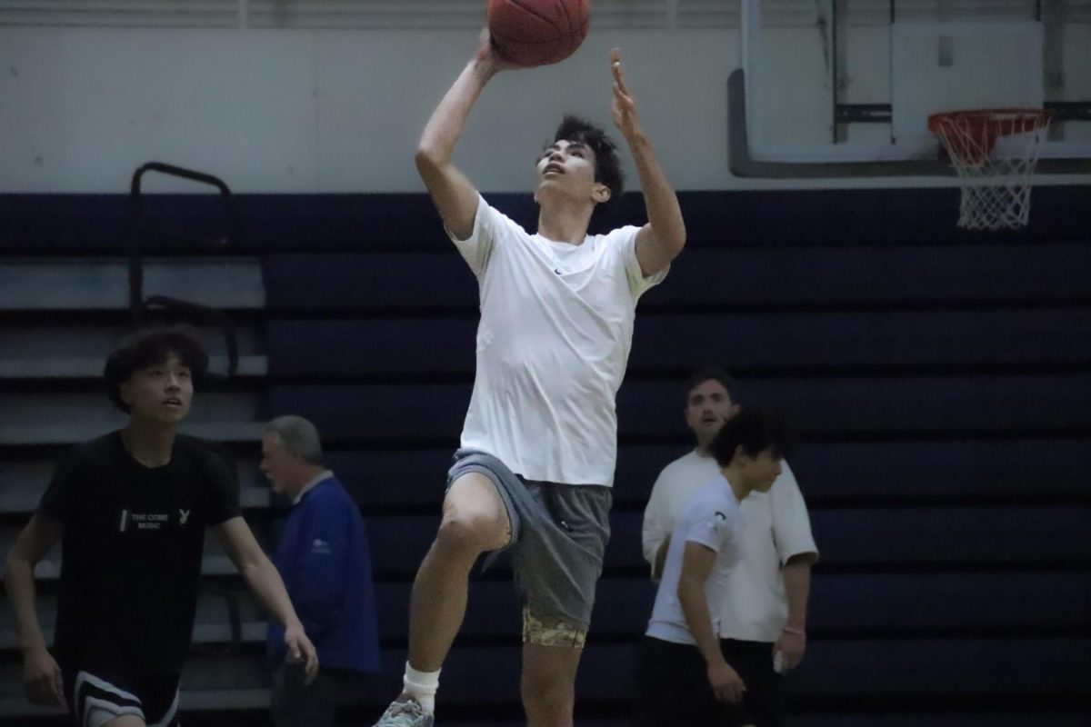 Jordan Rice leaps into the air, aiming for a layup as he drives toward the basket during a practice session. Rice focused on his scoring skills during the varsity tryout practice. 