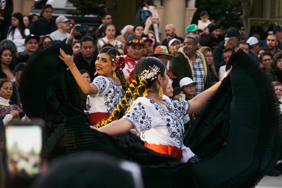 Dancers dressed in huipil garments and long skirts dance back to back with each other. Huipils are a traditional garment worn commonly by indigenous women in parts of Central America. Huipils today have become a sign of the wearer's community and ethnicity, as each culture has its way of making and decorating the garment.