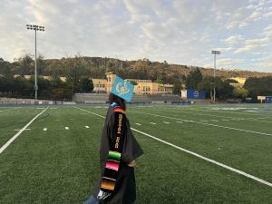 A Latina student proudly graduates high school with a sarapa sash hung around her neck as a representation of a her culture. The importance of working hard and gaining an education are core values within the Latino community.