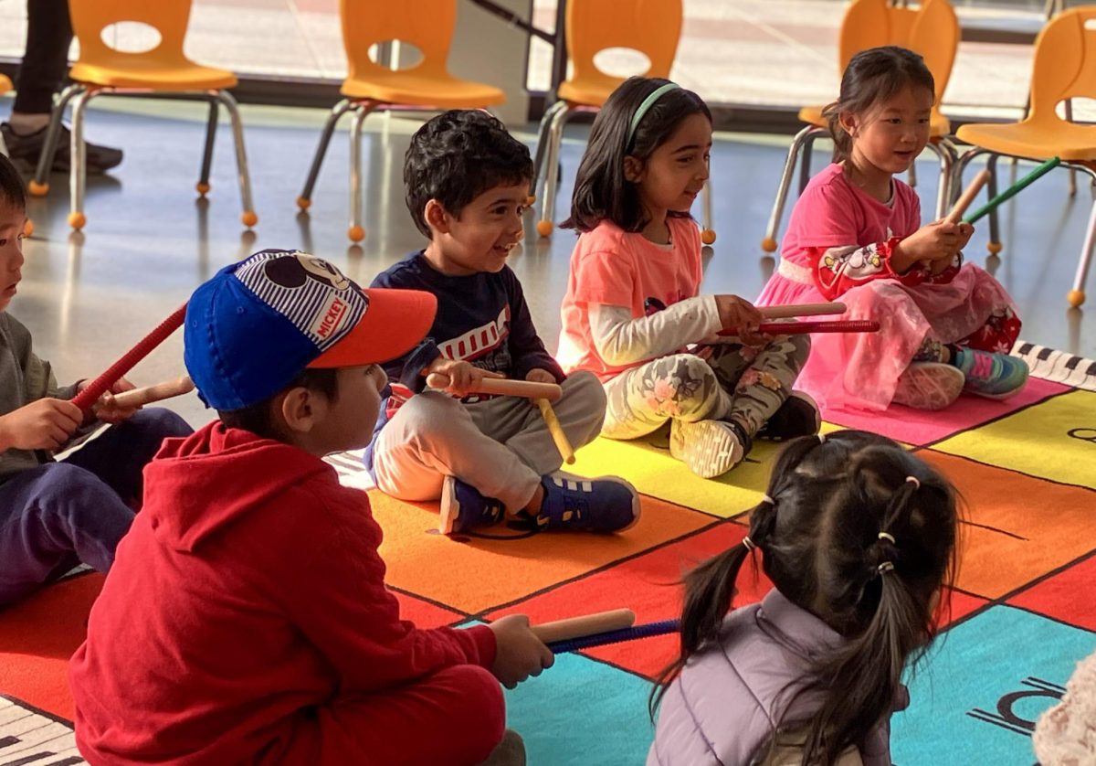 Children play with rhythm sticks during the music section at the Community School of Music and Arts (CSMA) free event. 