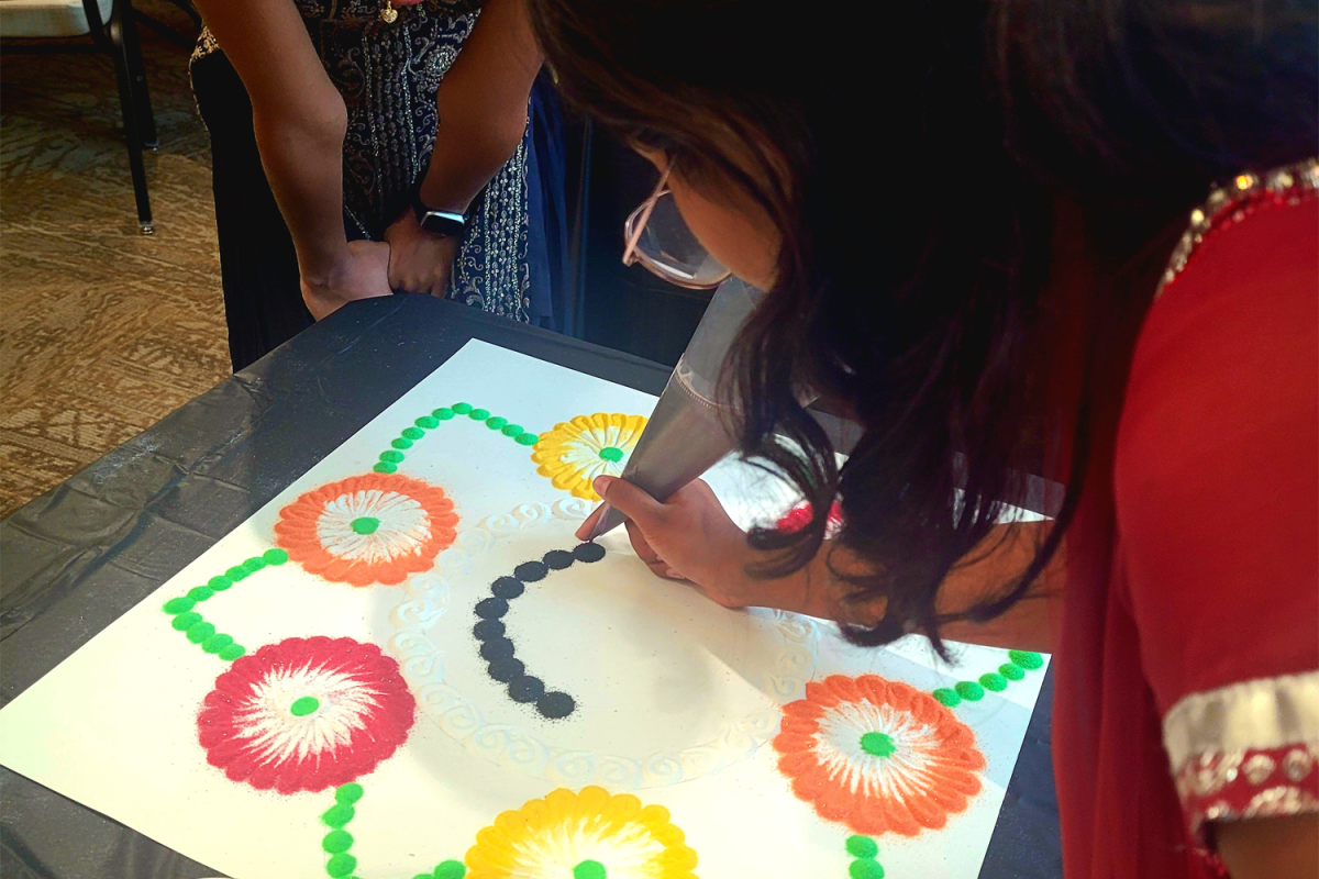 Aanya Myneni, a contestant for the rangoli contest, works on adding the circles of sand to her teams piece. Among other events at the Peninsula Gujarati Association's annual Diwali celebration, the contest offered an exciting environment for creative expression with traditional art forms. 