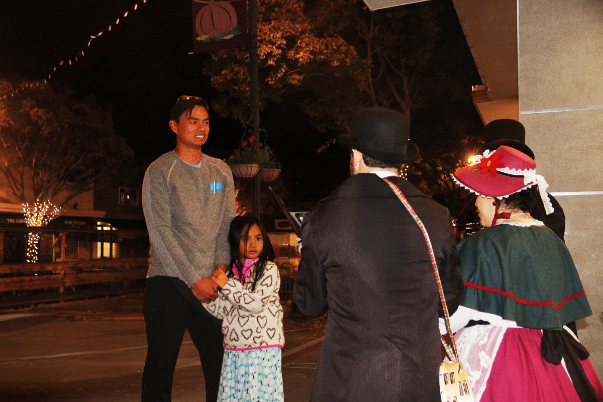 A group of carolers sing to a family along the street. "The carolers add to the magic of shopping during 'Thursday Night Lights,'" said event attendee Kate Elliott. "Normally, I shop online, but experiencing this sense of community and meeting the faces behind these small businesses makes me want to support them more."