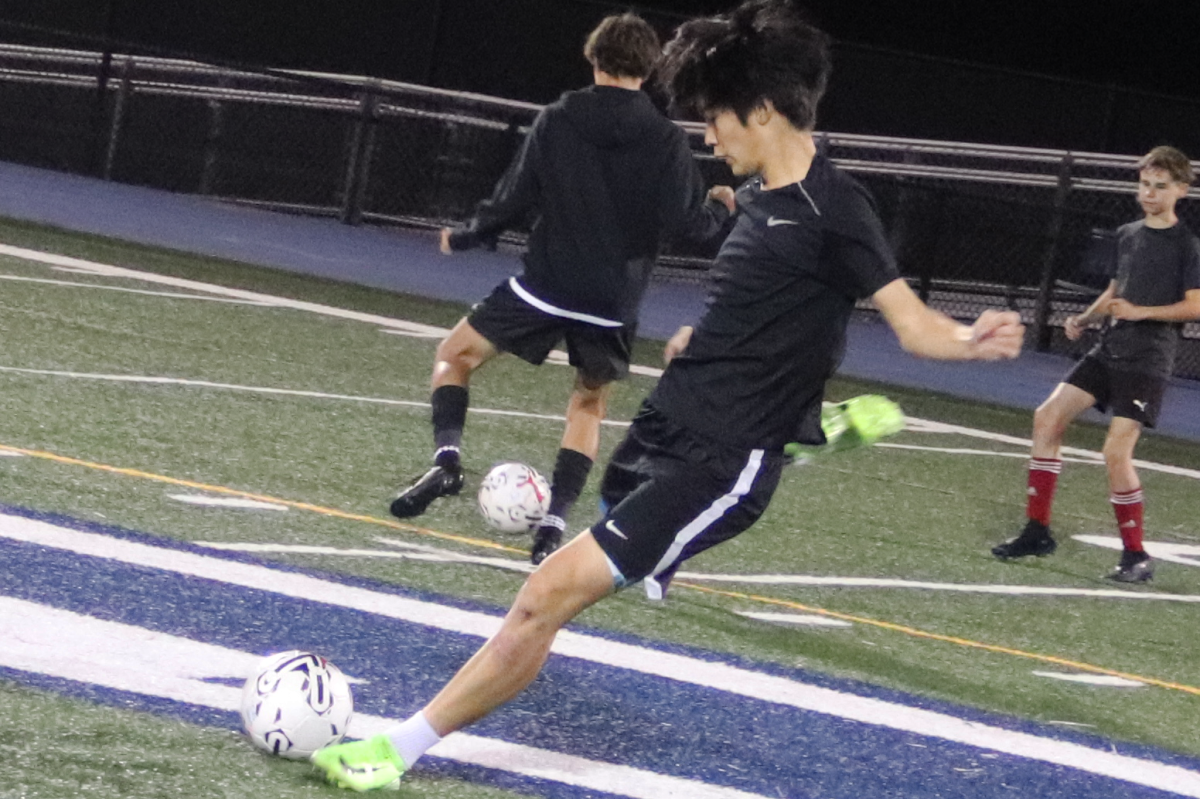 Wong plants his foot and winds up his right leg to make a pass to his teammate. Passing the ball before practice is a good warm up. This allowed Wong to be ready and on his feet later in practice.