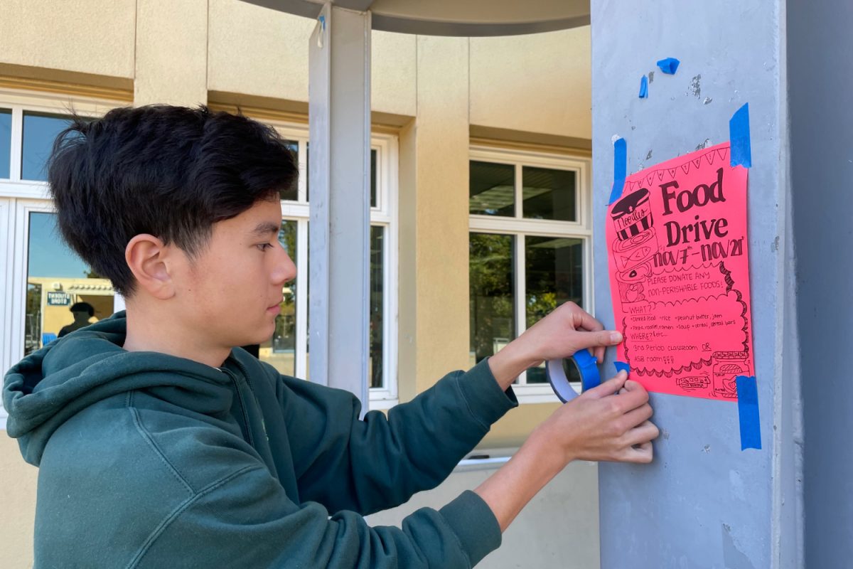 Ethan Lee, a sophomore at Carlmont, puts up flyers to promote this year's food Drive. Lee and several other members of ASB worked together to create these flyers as well as other forms of publicity. 