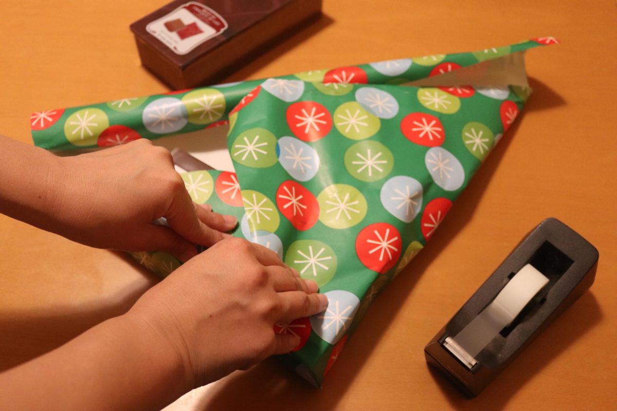 A person carefully wraps a gift, showcasing the unique and personal touches that come with gift giving, one of many holiday traditions. "Gift giving isn't an obligation, it's more a sign of affection. If I give you a gift, I shouldn't expect a gift in return," said Jasmine Lee, a sophomore at Carlmont High School.