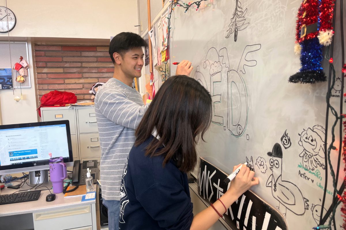 Ryan Chun and student Larissa Mi draw a quod erat demonstrandum (QED) on Chun's whiteboard after class. QED is a common math term used to show that a problem has been proved, and has become an inside joke in Chun's Precalculus Honors class. "Mr. Chun is very particular with wanting us to write it down on our worksheet," said Larissa Mi, one of his students. "We've questioned him a lot, but he still wants us to write it."