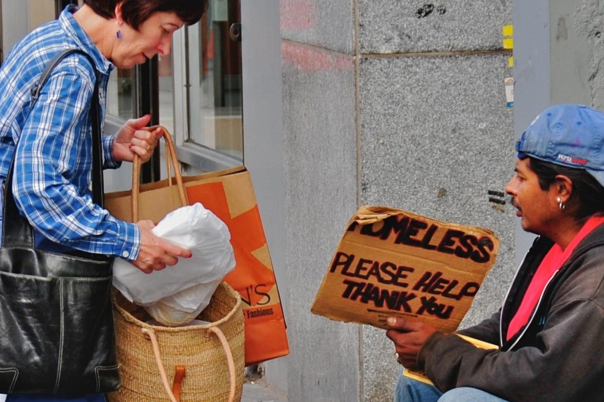 A woman distributes groceries and money to a homeless man on the street. Point-in-time count volunteers provided the homeless people they encountered with food, water, and gift cards in exchange for participating in a housing situation survey.