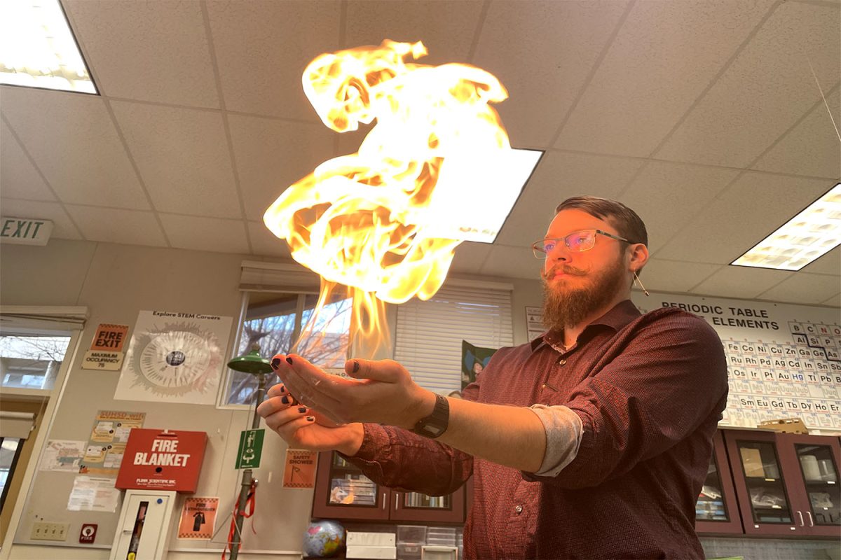 Micheal O'Neall lights soapy water with gas on fire for a demonstration. He uses water on his hand to ensure that he does not burn himself.