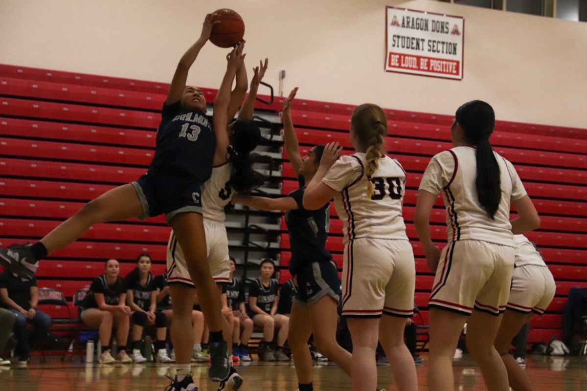 Junior Emerson Barajas jumps up to grab the rebounded ball while other players watch in anticipation. Barajas is a small forward for the Scots. "She played great defense against Aragons top scorer," said senior captain Willow Ishibashi-To.