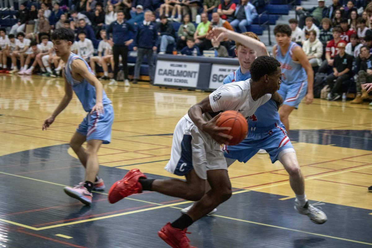 Carlmont senior Jeremiah Phillips drives to the hoop with the ball. The ball was kept on his right side so it was harder to steal. The defenders arm was held up to prevent Phillips from going up to score.