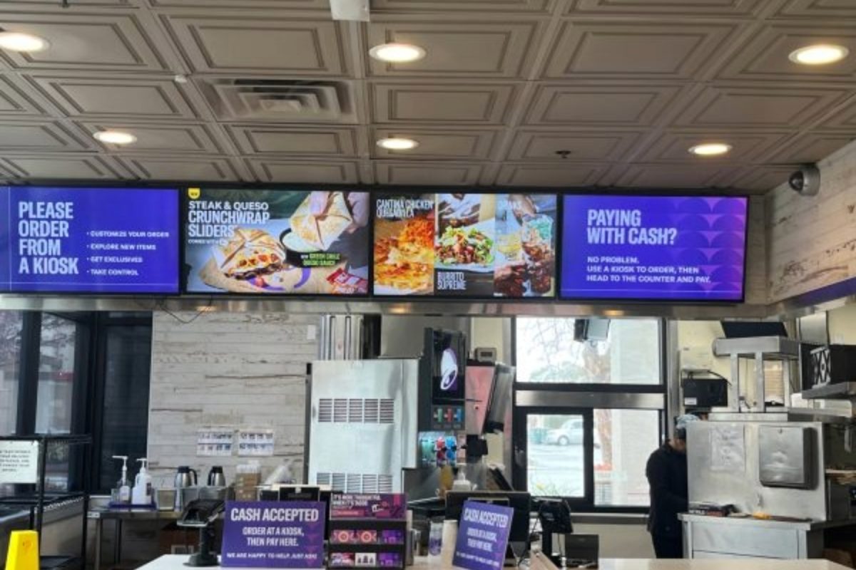 A Taco Bell location displays their new menu on smart screens. The new menu includes new creations like the Midnight Baja Blast, but omits beloved items like Nacho Fries, much to the chagrin of fans.