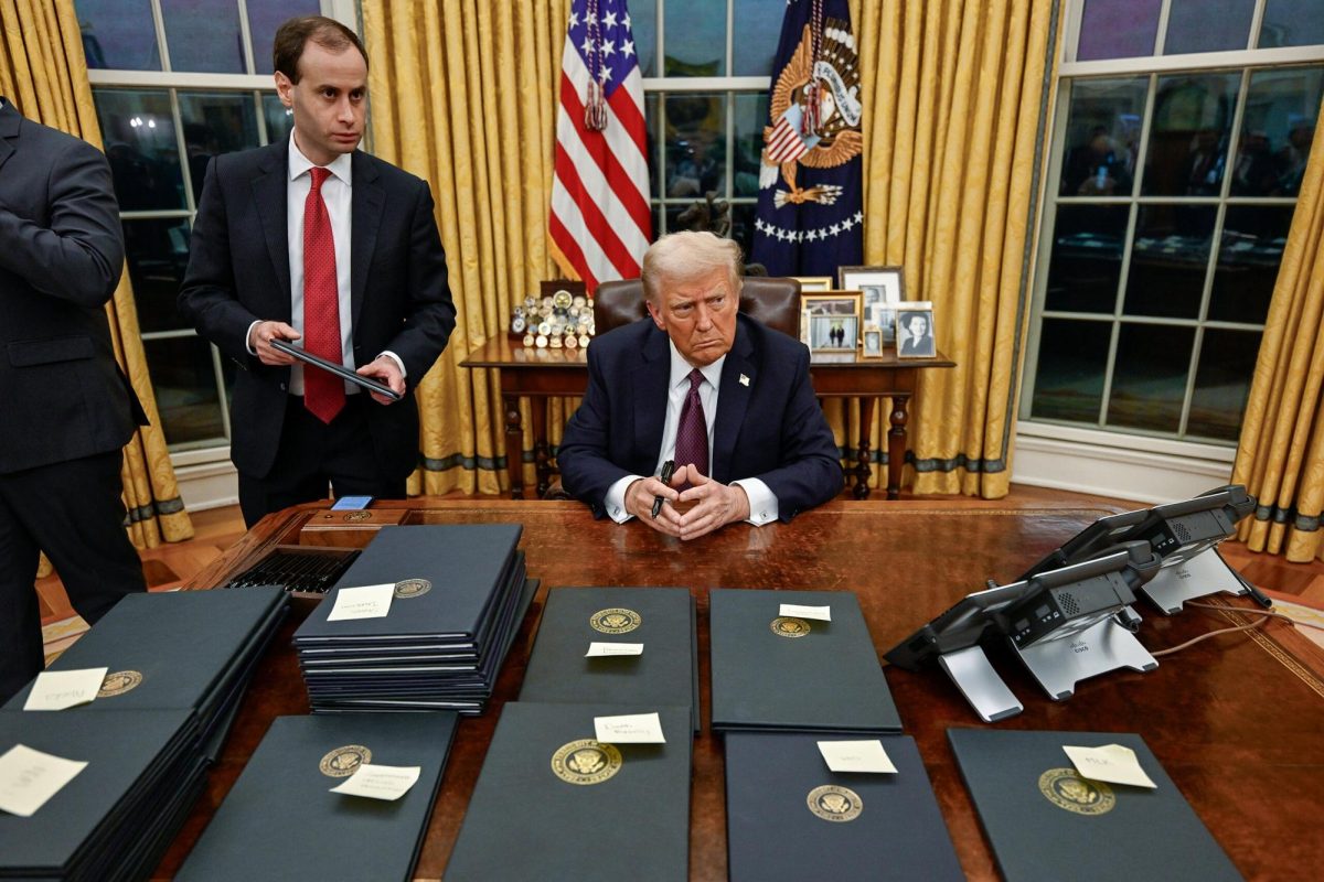 President Trump sits at his desk amongst stacks of executive orders he signed in the first two days of his second term.