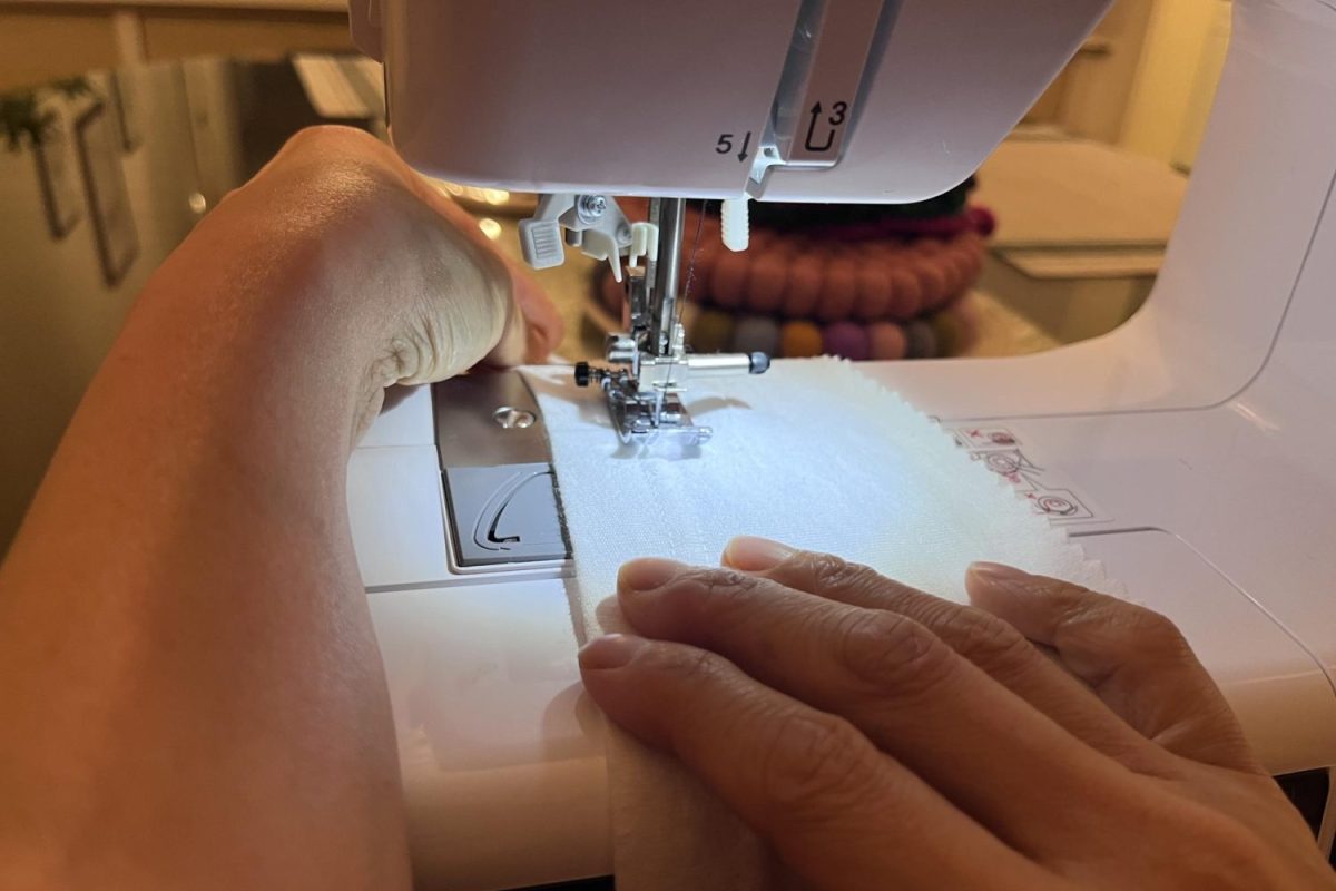 A local up-cycler goes to work repurposing a t-shirt hem into a waistband using a home sewing machine. Individuals experimenting in sewing their own clothes has been part of a larger trend in pushes for fashion sustainability.
