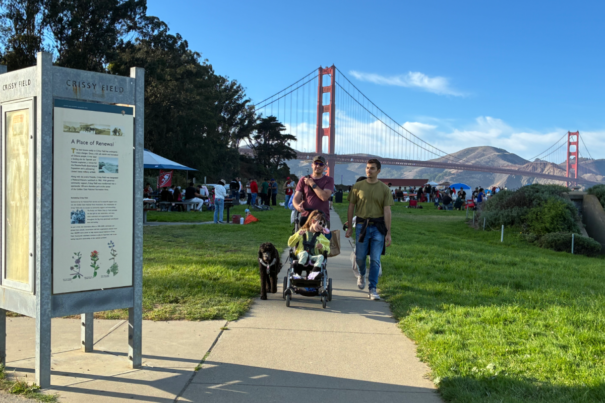 Families walk through Crissy Field, enjoying the afternoon weather and the view of the Golden Gate Bridge. Crissy Field is part of the Presidio of San Francisco, within the Golden Gate National Recreation Area. As such, it is cared for by the National Park Service and may be affected by changes in federal funding and staffing.