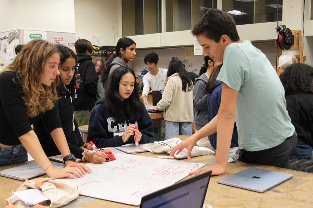 Daniel Tolkachov, a veteran robotics member, works with rookies to brainstorm designs for the M-Ayhem competition. One of the new students is Yusra Ali. "I'm excited to start designing the robot," Ali said. "I'm a little scared to try and come up with ideas for it."