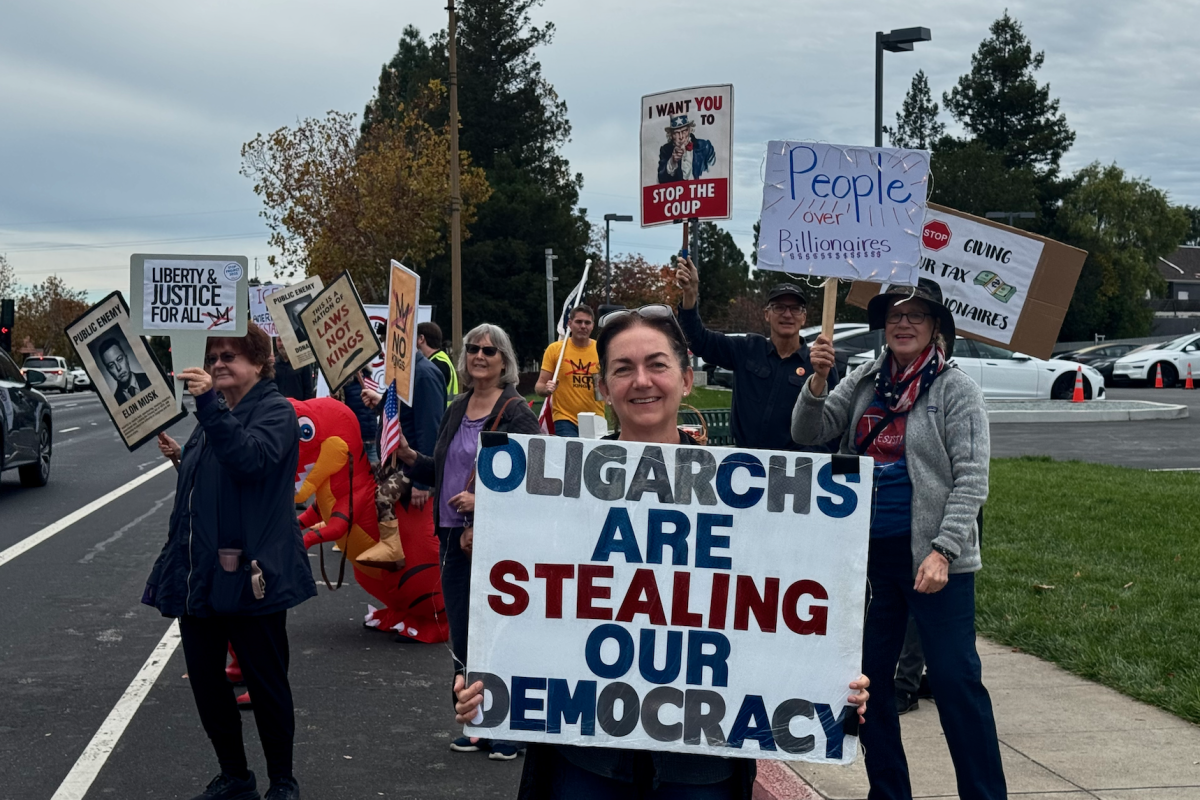 Protestors stand in front of the Tesla showroom in Los Gatos holding signs. “These protests are an opportunity to hold people like Elon Musk accountable,” said George Hoffman, an organizer of the protest.