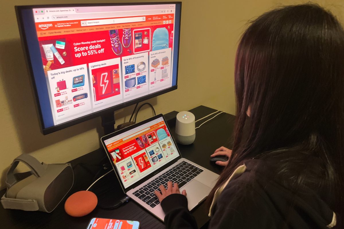 An online shopper browses for deals on Cyber Monday, surrounded by devices readily available for a purchase. Instead of interacting in crowded stores, many now shop alone at home, reducing chances for in-person social connection.
