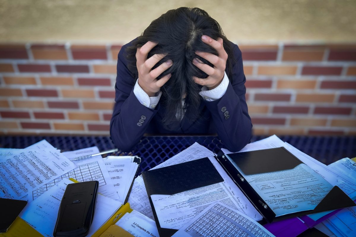 A person clutches their head, overwhelmed by the work that surrounds them. "Sometimes, hustle culture is more about putting in the hours and not considering personal health, having a work-life balance, getting the proper exercise, and having your family life suffer," said John Rowe, the Introduction to Business and Marketing and Communications teacher at Carlmont.