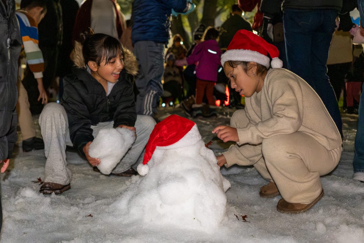 Two girls construct a snowman adorned with a festive hat. They used the snow provided by San Mateo Parks and Recreation for the event, which covered a small patch of grass where kids could play. “It’s really fun for the kids,” said a visiting resident from San Francisco who brought her daughter. “Snow fits perfectly with the Christmas spirit, and for kids who don’t usually get to see snow, this is such an exciting way to celebrate the holidays. Normally you’d have to drive up to Tahoe, so it’s nice to give them this experience.”