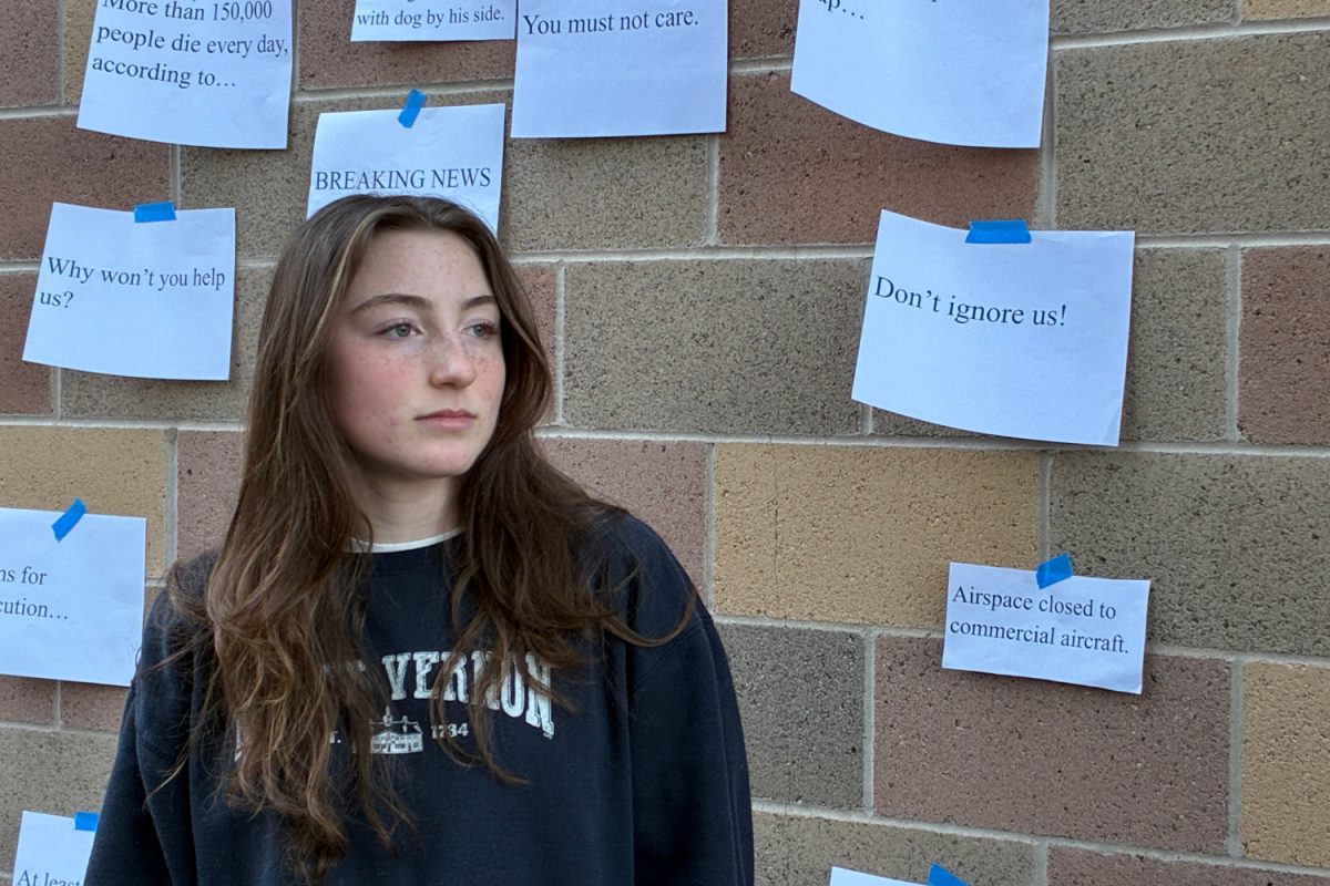 A teenager gazes into the distance, disregarding the tragic headlines posted behind her. Social media has exponentially increased our exposure to news, causing many people to become desensitized to displays of tragedy.