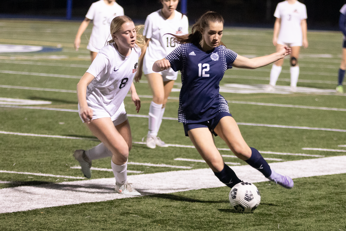 Sophomore Eloise Waight kicks the ball downfield with a Burlingame defender pressuring closely beside her. After the match, she reflected on her performance: “I think I can improve my communication and my first touches on the ball,” Waight said. The play came during an intense stretch of the game when Carlmont worked to maintain possession.