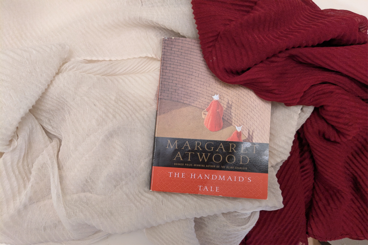 A copy of "The Handmaid's Tale" sits on red and white fabric, colors that symbolize the main character's uniform. Although it was published in 1985, it continues to be relevant today.
