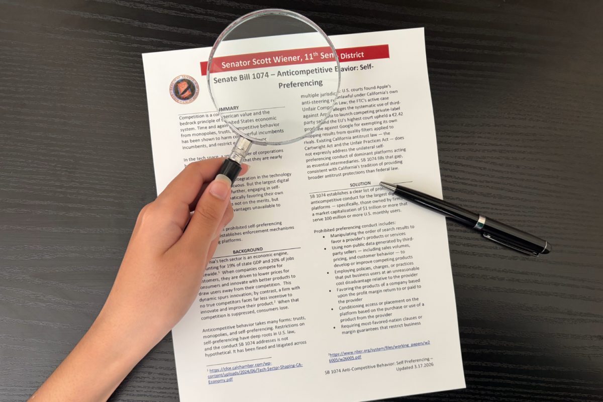 A student uses a magnifying glass to examine the fine print of Senate Bill 1074. The bill’s enforcement is modeled after the Cartwright Act, California’s 1907 antitrust law, to ensure digital platforms follow the same competition standards. “Let a thousand flowers bloom and let’s see what the good experience feels like when there are actually competitors competing for our business,” said Teri Olle, vice president of Economic Security California Action.