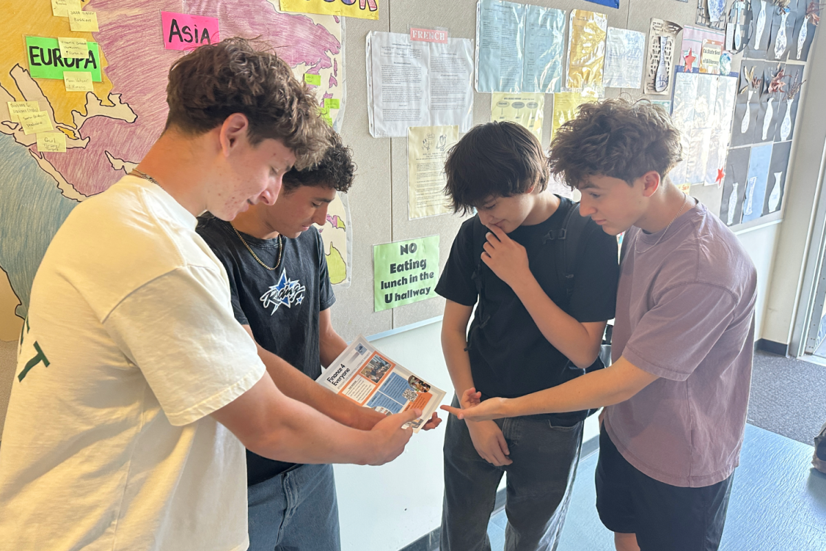 Finance4Everyone founders Raziel Yanovsky, Gianni Haggarty, and Max Rich-Gayko teach a student about their program. Finance4Everyone is a student-led organization that educates people about financial literacy. "We’ve done some community outreach events, like at the San Carlos Farmers Market, and we’ve done stuff at our school, like presentations," Haggarty said.