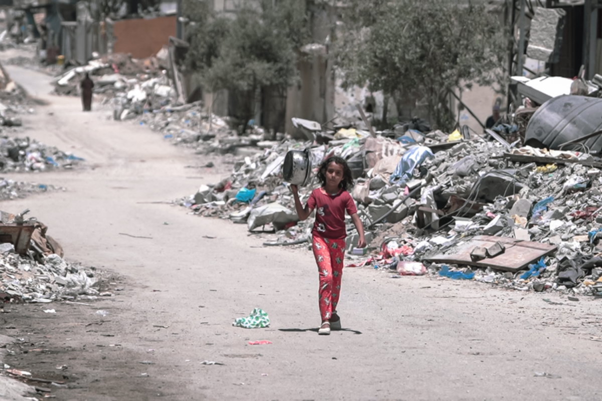 A young girl walks amongst the rubble of Gaza as she heads to get food. The surrounding destruction highlights the intense inequity that affects the people of Gaza, and further underscores the issues of a war that causes civilians to suffer. 