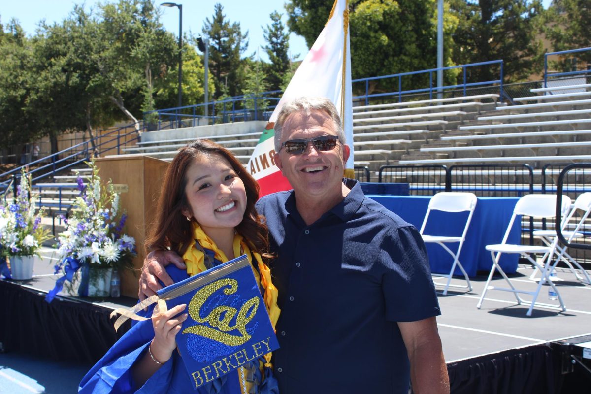 With a UC Berkeley cap in hand, Student Body Vice President Mia Ikeda and Activities Director Jim Kelly embrace at graduation. For many seniors like Ikeda, graduation marks the start of something new — the pathway of higher education.
